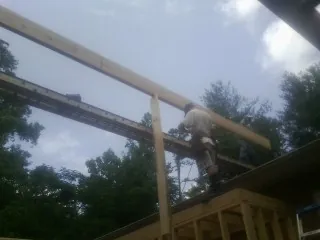 Carpenter setting a ridge beam over a new addition frame — Ice Dam Removal by Roofing Brothers in Pruden