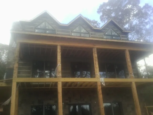 Dormers and porch framing on a large log home under construction — Roof Coating work by our crew in Pruden