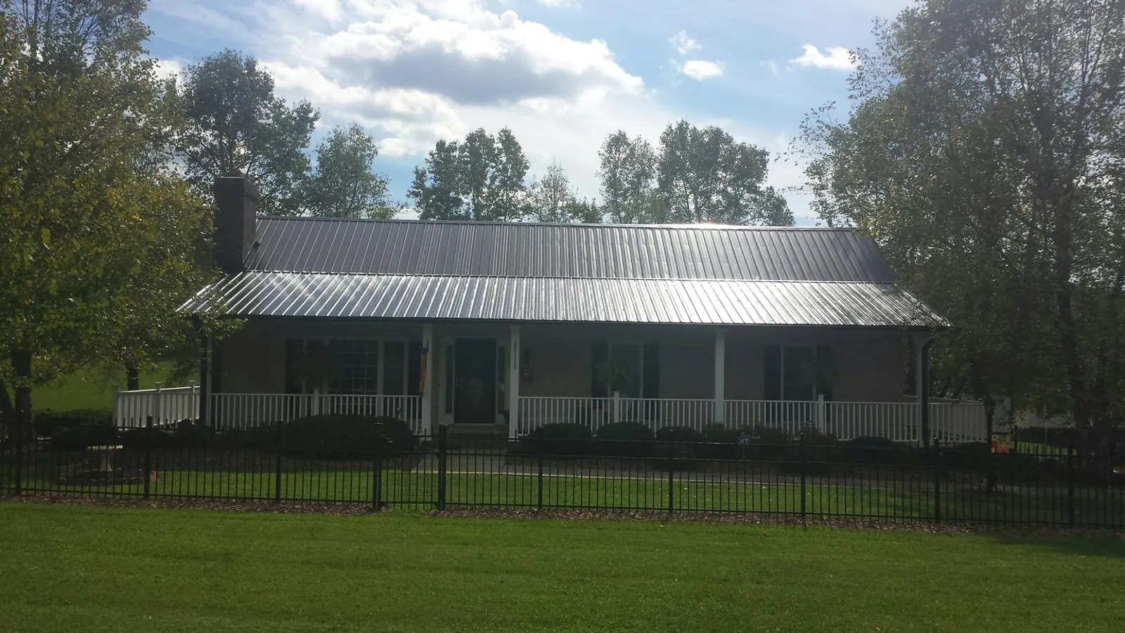 Gray metal roof on a brick ranch with a full width front porch — Gutter Guard Installation work by our crew in Pruden