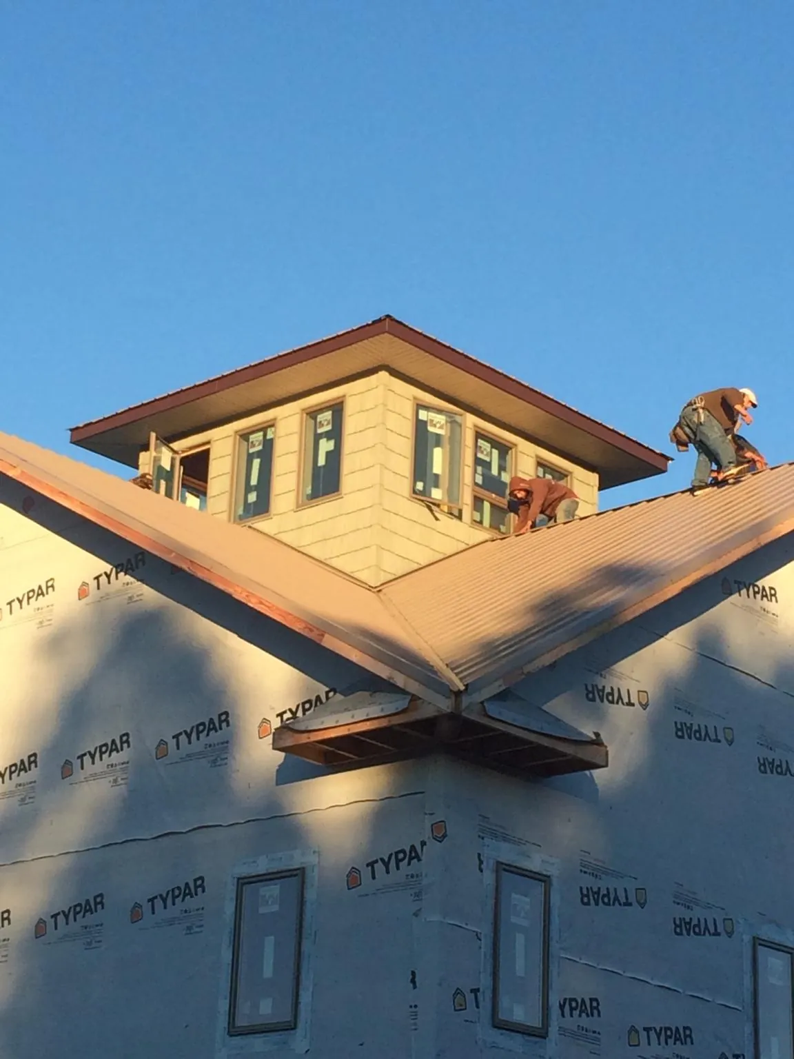 Roofers working around a rooftop cupola on a new metal roof at sunset — Roof Waterproofing in Pruden by Roofing Brothers